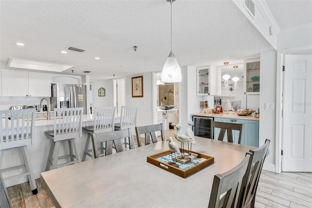 18500 Gulf Blvd Unit 503, Indian Shores, FL 33785 - dining room featuring a textured ceiling, beverage cooler, light wood-style floors, crown molding, and recessed lighting