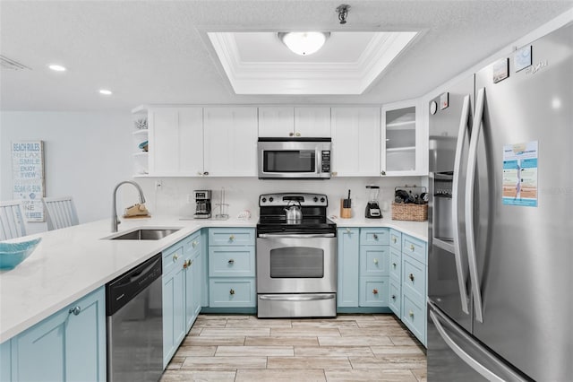 18500 Gulf Blvd Unit 503, Indian Shores, FL 33785 - kitchen with stainless steel appliances, blue cabinetry, a raised ceiling, ornamental molding, and light countertops
