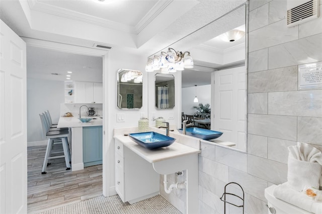 18500 Gulf Blvd Unit 503, Indian Shores, FL 33785 - bathroom featuring a tray ceiling, ornamental molding, wood finished floors, and vanity
