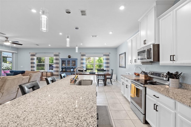 10618 Daybreak Gln, Parrish, FL 34219 - kitchen with appliances with stainless steel finishes, healthy amount of natural light, white cabinets, light stone countertops, and recessed lighting