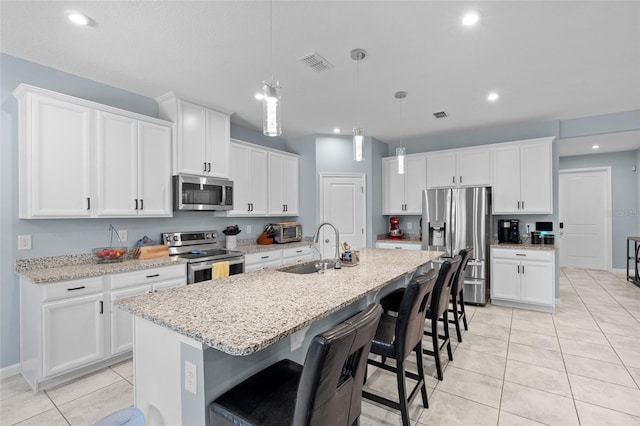 10618 Daybreak Gln, Parrish, FL 34219 - kitchen with appliances with stainless steel finishes, light tile patterned floors, a kitchen breakfast bar, white cabinets, and a center island with sink