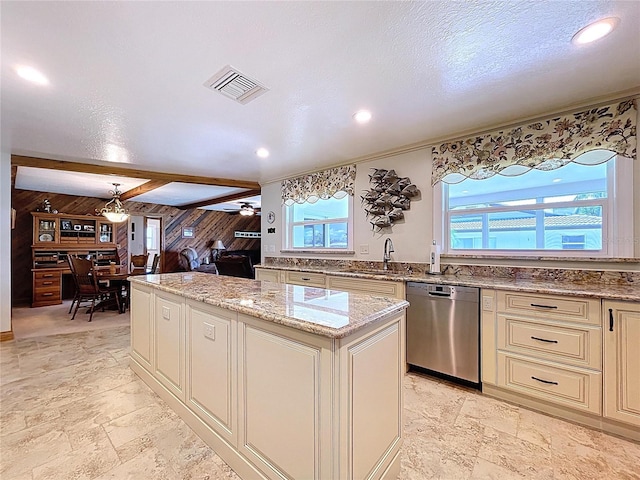 11141 Carla Dr, Largo, FL 33774 - kitchen with dishwasher, cream cabinets, wooden walls, a kitchen island, and stone tile flooring