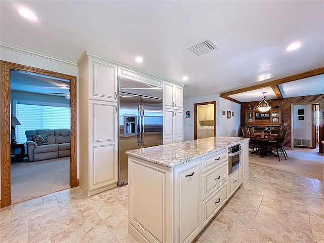 11141 Carla Dr, Largo, FL 33774 - kitchen with stainless steel built in fridge, washing machine and dryer, stone tile flooring, light stone countertops, and white cabinets