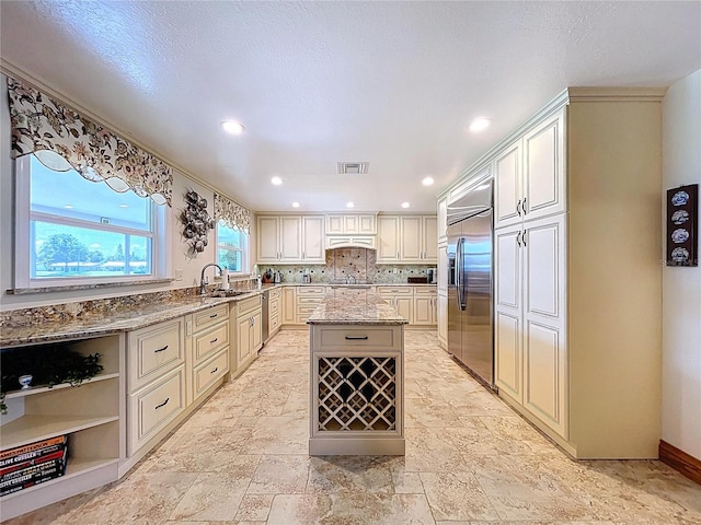 11141 Carla Dr, Largo, FL 33774 - kitchen with built in fridge, light stone counters, a center island, stone tile flooring, and tasteful backsplash