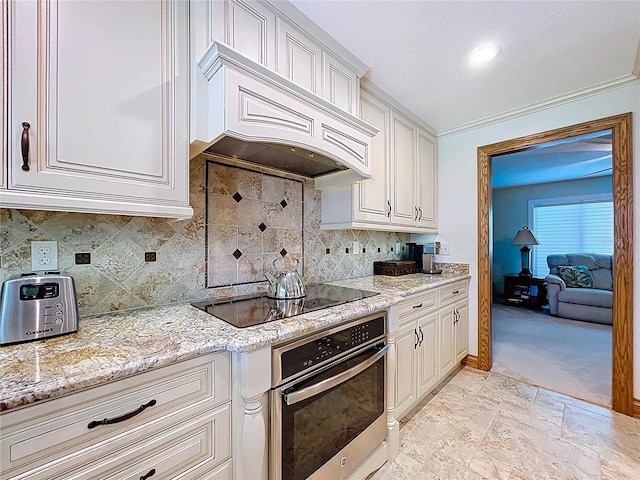 11141 Carla Dr, Largo, FL 33774 - kitchen featuring oven, premium range hood, black electric cooktop, and light stone counters