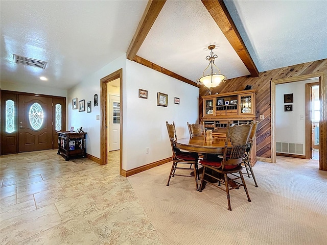 11141 Carla Dr, Largo, FL 33774 - dining space featuring wooden walls, beam ceiling, stone tile floors, and a textured ceiling