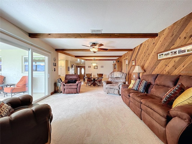 11141 Carla Dr, Largo, FL 33774 - living room featuring light carpet, beamed ceiling, wooden walls, a ceiling fan, and a textured ceiling
