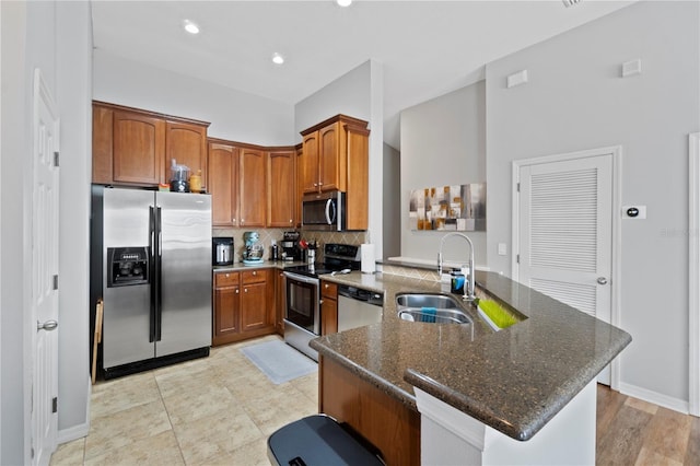 6734 Breezy Palm Dr, Riverview, FL 33578 - kitchen featuring appliances with stainless steel finishes, a peninsula, dark stone counters, decorative backsplash, and brown cabinetry