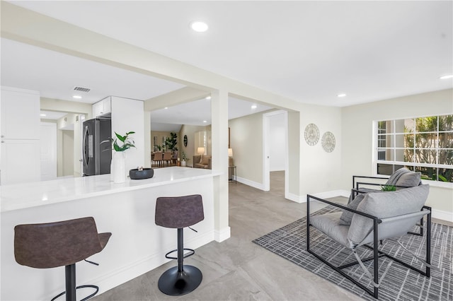 17601 Sterling Ter, Redington Shores, FL 33708 - kitchen with freestanding refrigerator, white cabinetry, recessed lighting, a breakfast bar, and light countertops