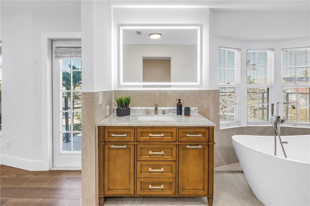 17601 Sterling Ter, Redington Shores, FL 33708 - bathroom featuring a freestanding bath, vanity, tile walls, and wood finished floors