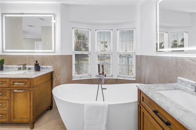 17601 Sterling Ter, Redington Shores, FL 33708 - full bath with tile walls, two vanities, a soaking tub, healthy amount of natural light, and wainscoting