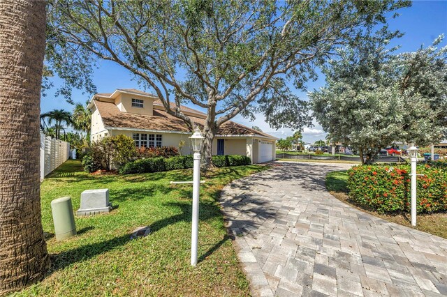 17601 Sterling Ter, Redington Shores, FL 33708 - view of front of house with decorative driveway, an attached garage, a front lawn, and stucco siding
