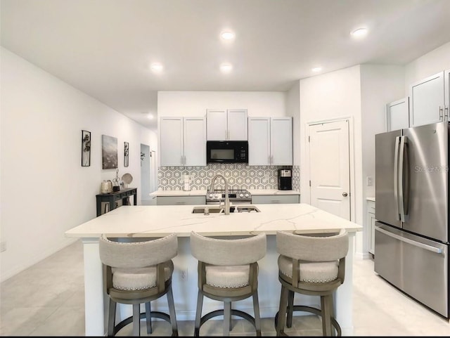 4282 Salt Springs Ln, Lakeland, FL 33811 - kitchen with freestanding refrigerator, black microwave, a kitchen bar, backsplash, and recessed lighting