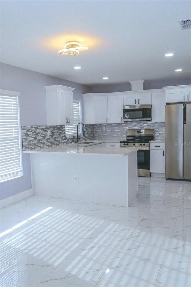 1302 Highview Rd, Brandon, FL 33510 - kitchen with appliances with stainless steel finishes, light marble finish flooring, backsplash, white cabinetry, and recessed lighting
