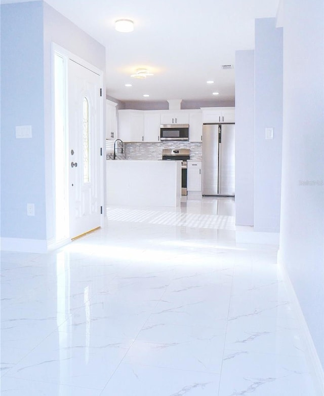 1302 Highview Rd, Brandon, FL 33510 - kitchen with stainless steel appliances, decorative backsplash, white cabinets, light countertops, and light marble finish floors
