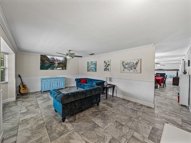 2937 Eagles Nest Rd, Fruitland Park, FL 34731 - living area featuring a ceiling fan, a textured ceiling, ornamental molding, a wainscoted wall, and light marble finish floors