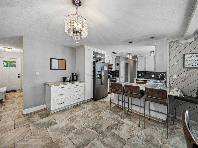 2937 Eagles Nest Rd, Fruitland Park, FL 34731 - kitchen featuring a textured ceiling, a chandelier, appliances with stainless steel finishes, a peninsula, and white cabinets