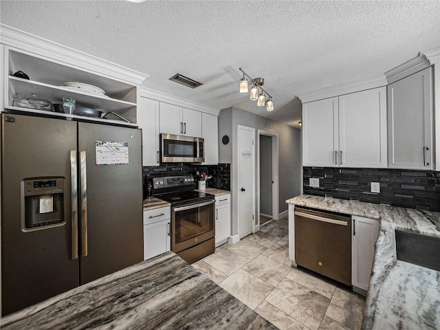 2937 Eagles Nest Rd, Fruitland Park, FL 34731 - kitchen with stainless steel appliances, backsplash, a textured ceiling, white cabinetry, and light stone counters