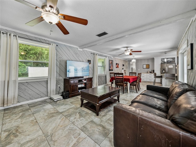 2937 Eagles Nest Rd, Fruitland Park, FL 34731 - living room with a ceiling fan, healthy amount of natural light, wood walls, light marble finish floors, and a textured ceiling