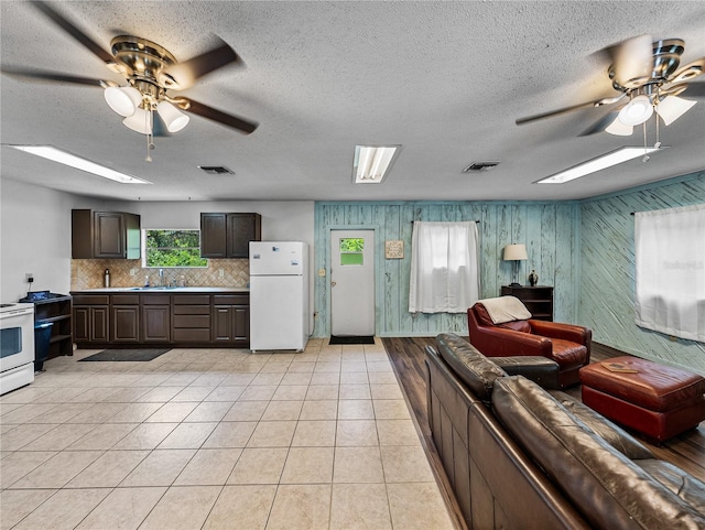 2937 Eagles Nest Rd, Fruitland Park, FL 34731 - living room featuring ceiling fan, wood walls, light tile patterned flooring, a skylight, and a textured ceiling
