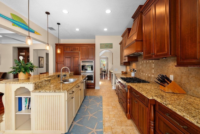 703 Islebay Dr, Apollo Beach, FL 33572 - kitchen with arched walkways, custom range hood, stainless steel appliances, tasteful backsplash, and a center island with sink