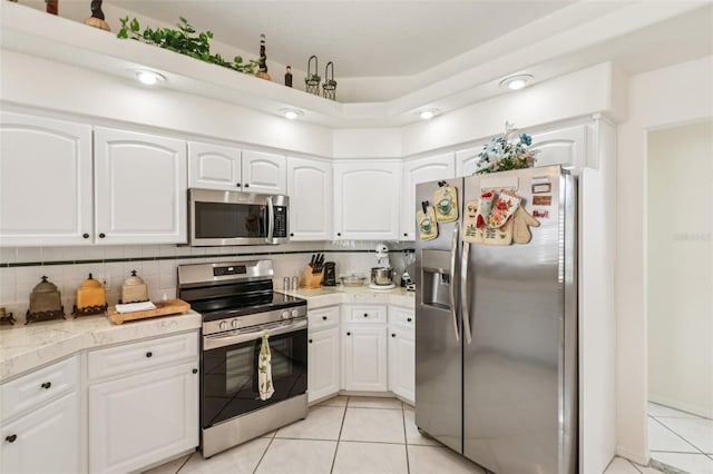 8704 Cypress Lakes Blvd, New Port Richey, FL 34653 - kitchen featuring appliances with stainless steel finishes, light tile patterned flooring, tasteful backsplash, and white cabinets