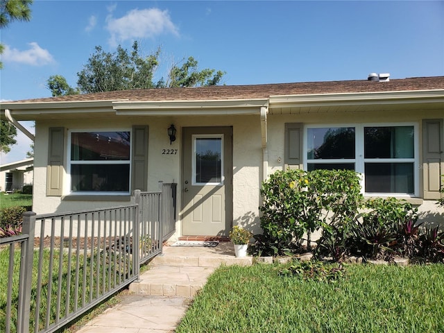 2227 Grenadier Dr Unit 140, Sun City Center, FL 33573 - view of exterior entry featuring stucco siding, a shingled roof, and covered porch