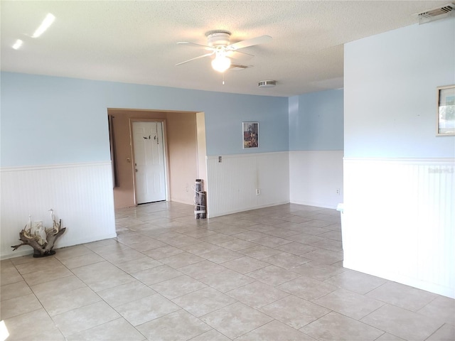 2227 Grenadier Dr Unit 140, Sun City Center, FL 33573 - empty room with wainscoting, a ceiling fan, a textured ceiling, and light tile patterned flooring