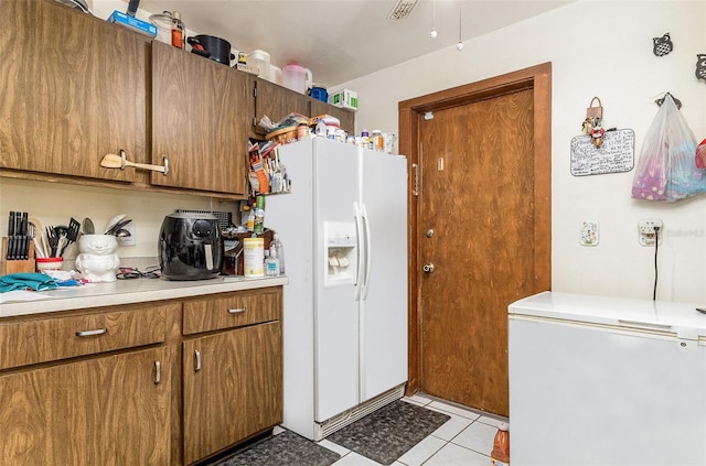 712 Divot Ln, Poinciana, FL 34759 - kitchen with refrigerator, white fridge with ice dispenser, brown cabinets, light countertops, and light tile patterned floors
