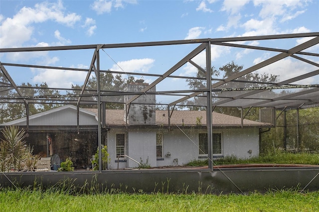 712 Divot Ln, Poinciana, FL 34759 - rear view of house featuring stucco siding and glass enclosure