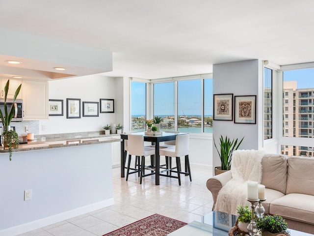 660 Island Way Unit 703, Clearwater Beach, FL 33767 - kitchen with stainless steel microwave, white cabinetry, light tile patterned floors, decorative backsplash, and open floor plan