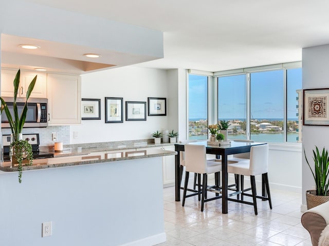 660 Island Way Unit 703, Clearwater Beach, FL 33767 - kitchen featuring stainless steel appliances, decorative backsplash, white cabinets, light stone counters, and a peninsula
