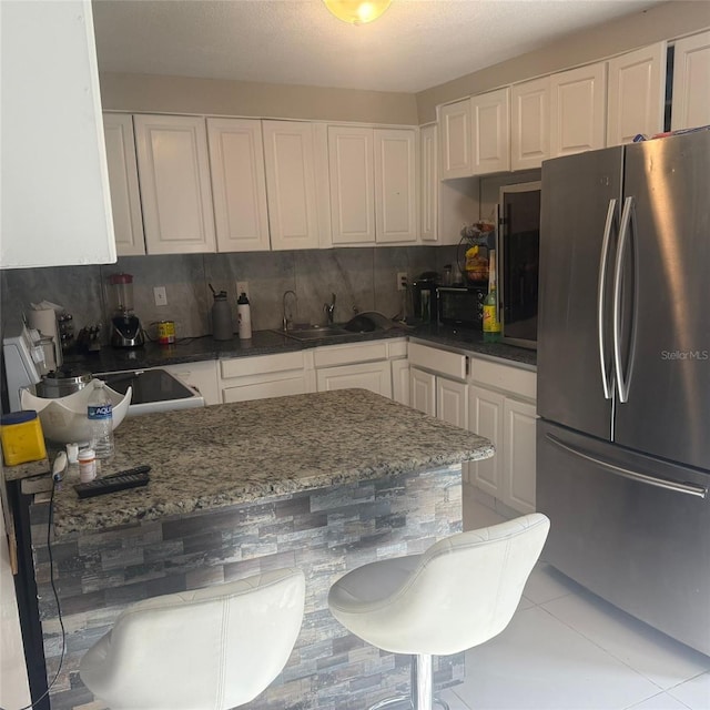 10004 Ethel St, Gibsonton, FL 33534 - kitchen featuring freestanding refrigerator, white cabinetry, dark stone countertops, light tile patterned flooring, and range with electric cooktop