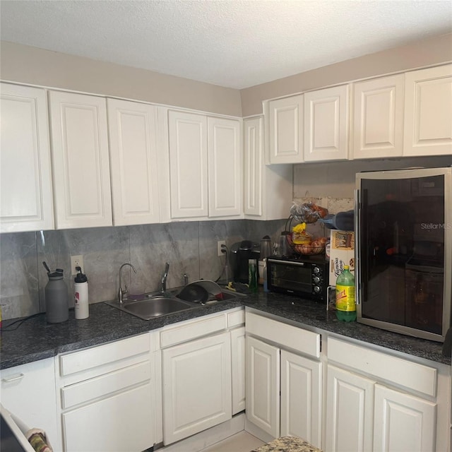 10004 Ethel St, Gibsonton, FL 33534 - kitchen with white cabinetry, backsplash, dark countertops, and a textured ceiling
