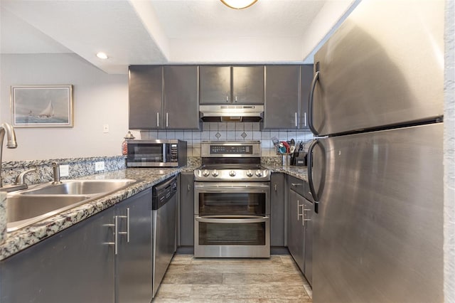 4905 25th St W Unit 101, Bradenton, FL 34207 - kitchen featuring stainless steel appliances, under cabinet range hood, light wood-type flooring, backsplash, and dark brown cabinets