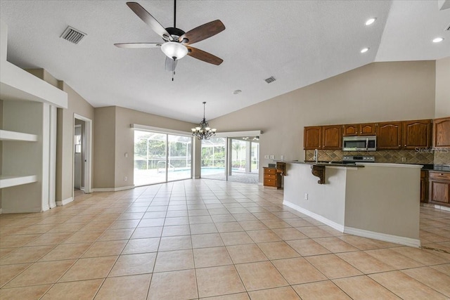 816 Sandringham Ln, Lutz, FL 33549 - kitchen featuring stainless steel microwave, a ceiling fan, open floor plan, a chandelier, and tasteful backsplash