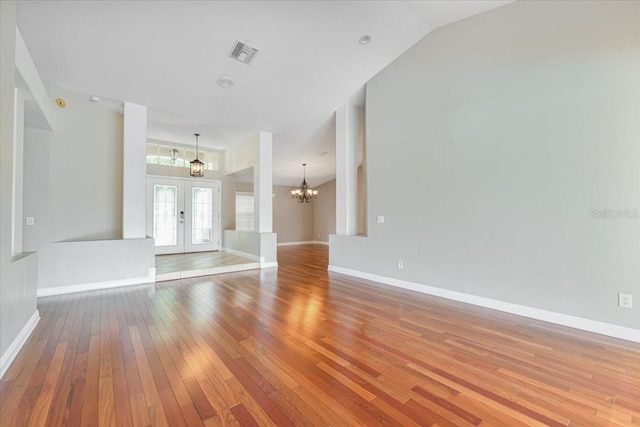 816 Sandringham Ln, Lutz, FL 33549 - unfurnished living room featuring a chandelier, french doors, hardwood / wood-style flooring, and vaulted ceiling