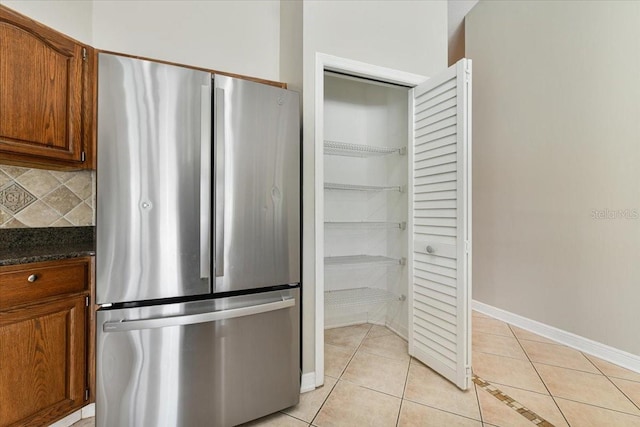 816 Sandringham Ln, Lutz, FL 33549 - kitchen with freestanding refrigerator, light tile patterned flooring, backsplash, and brown cabinetry