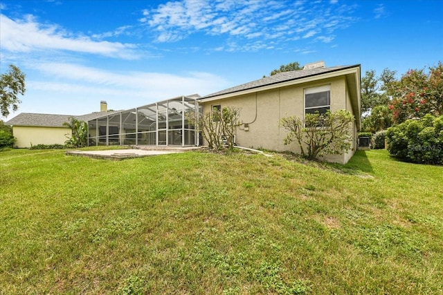 816 Sandringham Ln, Lutz, FL 33549 - rear view of house featuring stucco siding, a lawn, glass enclosure, and a chimney
