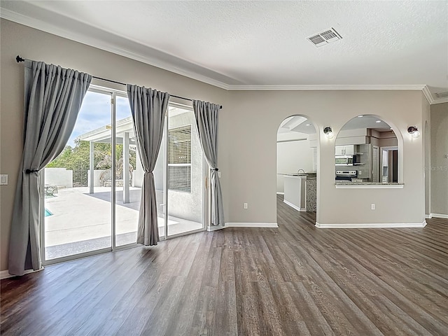 8303 Nightwalker Rd, Weeki Wachee, FL 34613 - empty room with dark wood-type flooring, arched walkways, ornamental molding, and a textured ceiling