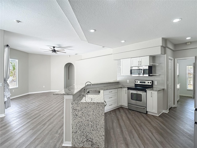 8303 Nightwalker Rd, Weeki Wachee, FL 34613 - kitchen with stainless steel appliances, a peninsula, a textured ceiling, dark wood-type flooring, and ceiling fan