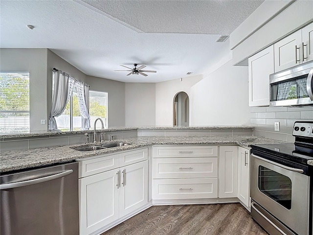 8303 Nightwalker Rd, Weeki Wachee, FL 34613 - kitchen featuring stainless steel appliances, a textured ceiling, white cabinetry, a ceiling fan, and dark wood-style flooring