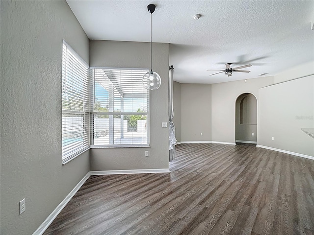 8303 Nightwalker Rd, Weeki Wachee, FL 34613 - unfurnished room featuring a textured wall, wood finished floors, ceiling fan, arched walkways, and a textured ceiling
