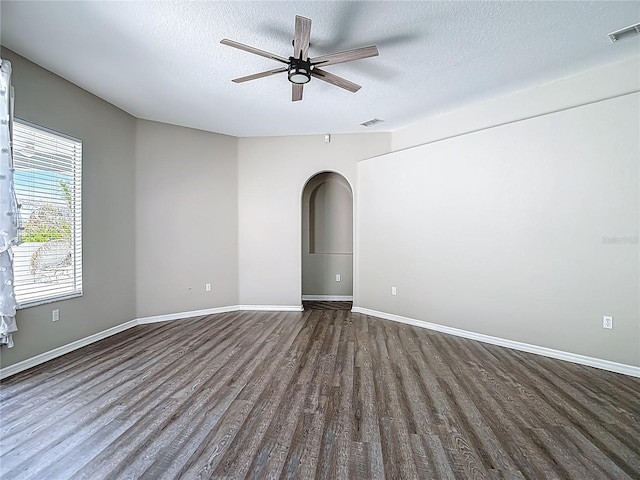 8303 Nightwalker Rd, Weeki Wachee, FL 34613 - unfurnished room with dark wood-style flooring, a textured ceiling, a ceiling fan, and arched walkways