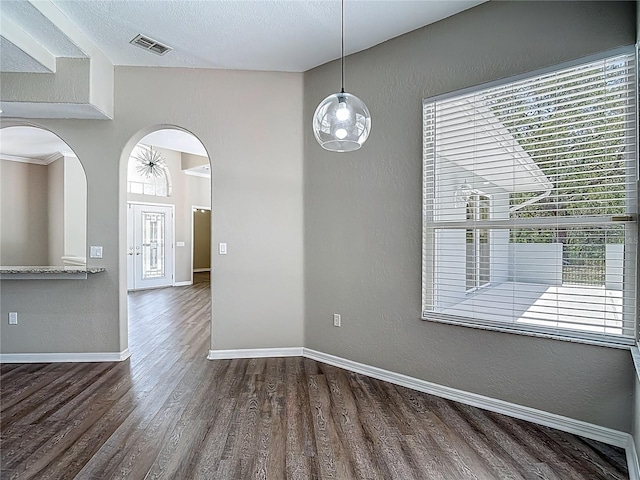 8303 Nightwalker Rd, Weeki Wachee, FL 34613 - unfurnished dining area featuring plenty of natural light, wood finished floors, arched walkways, and a textured wall
