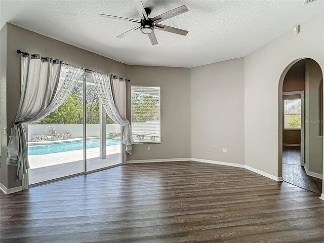 8303 Nightwalker Rd, Weeki Wachee, FL 34613 - spare room featuring arched walkways, dark wood-style flooring, ceiling fan, and a textured ceiling
