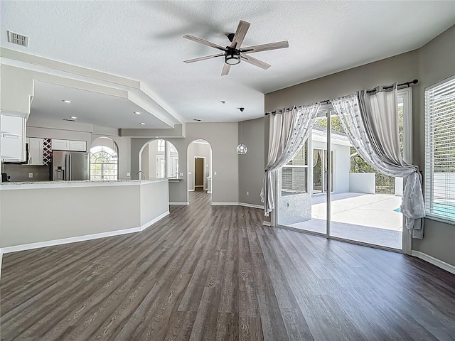 8303 Nightwalker Rd, Weeki Wachee, FL 34613 - unfurnished living room with dark wood-style floors, arched walkways, ceiling fan, a textured ceiling, and healthy amount of natural light
