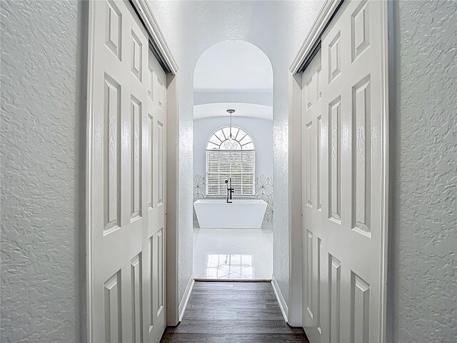 8303 Nightwalker Rd, Weeki Wachee, FL 34613 - corridor featuring a textured wall, arched walkways, and dark wood-type flooring