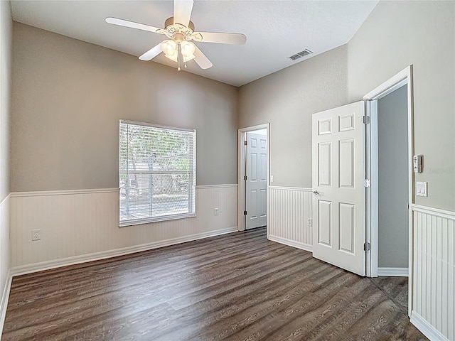 8303 Nightwalker Rd, Weeki Wachee, FL 34613 - unfurnished bedroom featuring dark wood-style flooring, a wainscoted wall, and ceiling fan