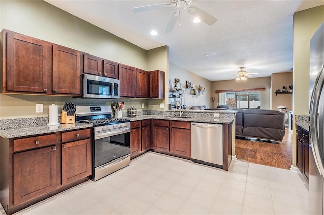 19351 Haskell Pl, Land O Lakes, FL 34638 - kitchen with stainless steel appliances, a ceiling fan, open floor plan, a peninsula, and light stone counters